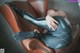 A woman laying on a brown leather chair with her legs crossed.