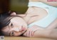 A young woman laying on a bed with her hand on her chin.