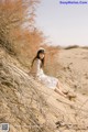 A woman sitting on top of a sand dune in the desert.