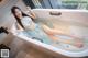 A woman laying in a bathtub with her feet in the water.