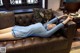 A woman laying on a brown leather couch in a living room.