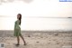 A woman in a green dress standing on a beach.