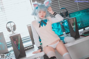 A woman in a white sweater and blue cat ears sitting at a desk.