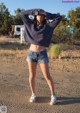 A woman standing in the middle of a dirt road.