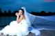 A woman in a wedding dress sitting on a dock.